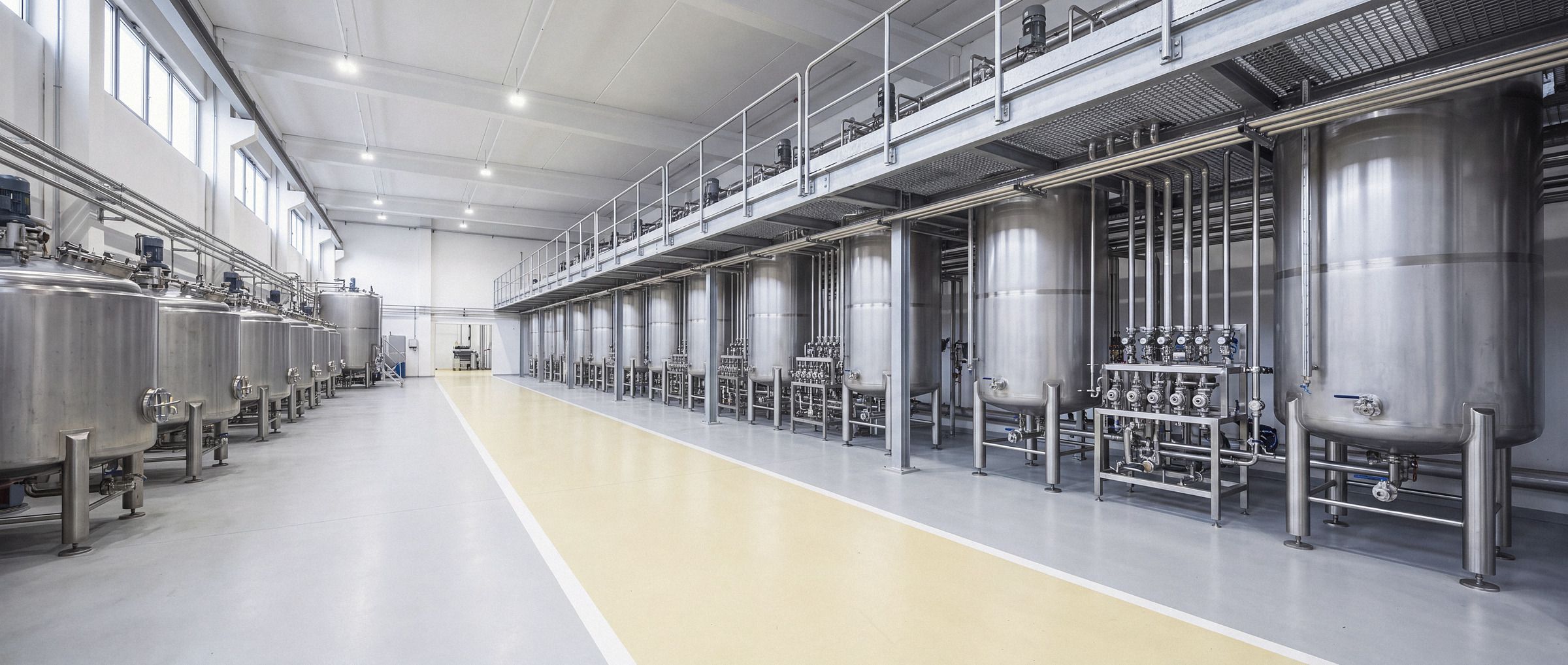 Interior de planta industrial química com tanques de mistura e tubulação.